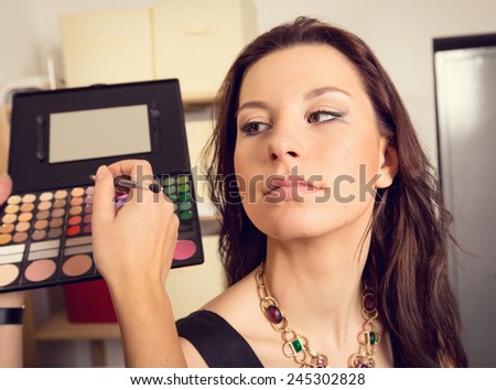 In the beauty salon. Girl doing makeup. Cosmetics and color palette for makeup. Cosmetics, woman, fashion, beauty, care, face, glamor, trend - the concept of a modern lifestyle. Work up artist.