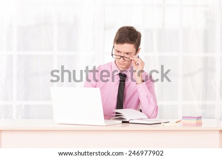 Man in business attire working at a laptop. Employee of the office. Student are trained in the office. Work with documents and computer. Trainee working in the office. Young man assistant manager.