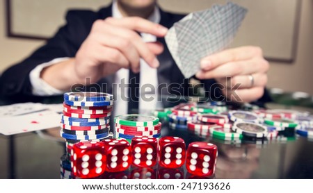 Hand close up. A man in a business suit sitting at the game table. Male player. Passion, cards, chips, alcohol, dice, gambling, casino - it is as male entertainment. Dangerous fun card game for money.