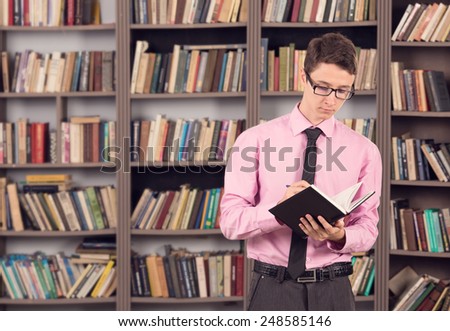 Male student uses to work through his subject material. Man student reading a book in the library of the institution. Male intern studying materials for their future profession. Buy in a bookstore.