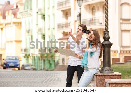 Man and woman tourists. They came on a trip to another city. Tourist, travel, map, binoculars, a pair of man and woman on a city street. Love story of two young travelers come on vacation, summer day.