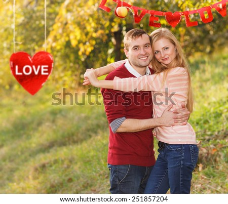 Love story between a man and a woman. Lifestyle of people. Trip during the holidays. Couple in love against a blurred background of the heart with the word love and a blurred background of city park.