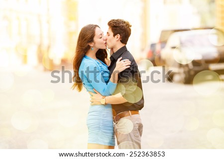 Kiss of two lovers in the city. Walking through the city. Love between two people. Honeymoon. Love story. Young happy couple in the city. Young man and beautiful woman on street. Spend their holidays.