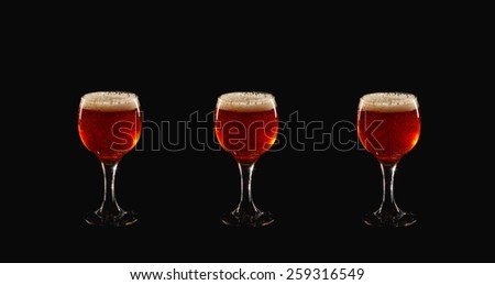 Glass goblet on a black background. In a glass of beer or wine is poured. Jet of liquid fills the glass. A glass of dark honey beer. Amber glass of wine. Three full glass goblet