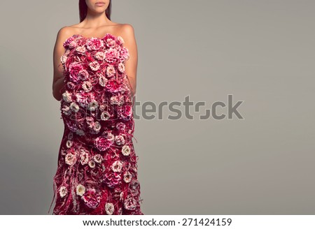 Woman in dress of red and pink flowers. Woman not face, just the body covered with flowers. Woman body flowers, gray background. Bouquet of flowers in the form of the female body. Concept art flower.