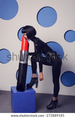 Woman paints her lips all face all lipstick. The girl fell asleep on a big red lipstick - face down. Fashionable topic shades of gray. Attractive woman in leather suit. Woman in leather suit