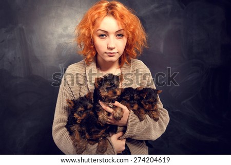 Woman beautiful young happy with long red hair in sweater holding five small dogs. Girl and five yorkshire terrier. Five puppies in the arms of a girl on a dark background.