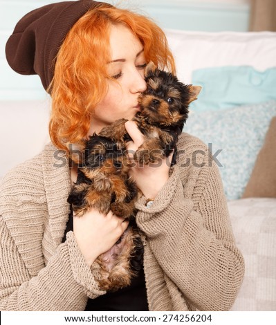 Young girl with a puppy of Yorkshire terrier. Beautiful reddish haired young woman holding a group of small terrier puppy York. Woman and puppy dog house in the room. Many puppies a woman in his arms.