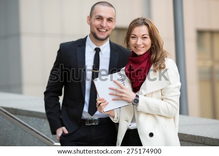 Portrait of a business woman against a blurred background with a man and office building. Business hours. Female student intern. Business people - man and woman. Successful group of business people.