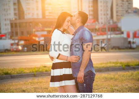 Love story, man and woman, love - concept of human life in a big modern city. Couple in love in the glow of the sunset on the background of urban buildings. Display a sense of love for each other.