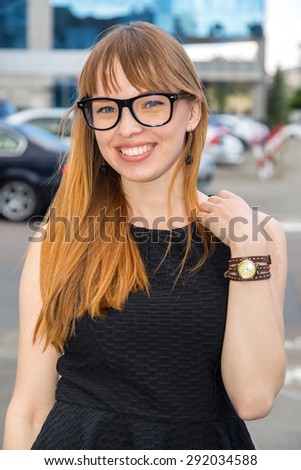 Woman smiling of joy. Happy mixed race female business woman on the city street and  office building and parking background. Business woman looking at camera. Woman wearing glasses smiling.