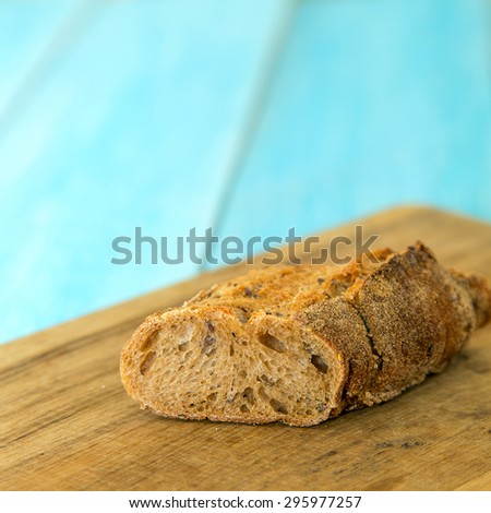 Bread on a light blue background. Delicious sliced bread on wooden table. Sliced bread lying on a wooden board. Slice of bread on a chopping board. Sliced rye bread on cutting board closeup.