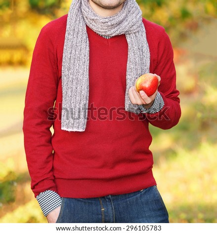Young handsome man, not face, holding a red apple in her hand. Man in red glasses on a background of the autumn park. Fresh air and a healthy kicking -  concept about the urban dweller. Lifestyle.