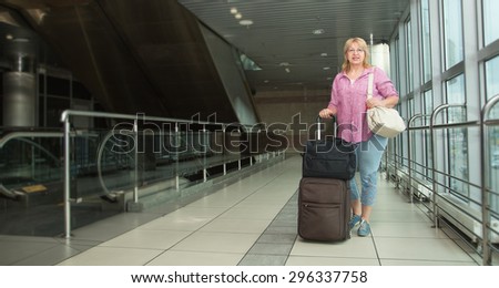 Adult woman is traveling. Woman with a suitcase goes on building the bus station, train station or airport. Retired woman embarks on a journey. Bags and suitcases for travel. Travel. Lifestyle.