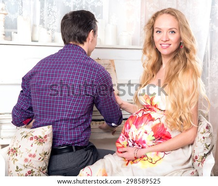 Happy family. Pregnant woman and her man. Pregnant happy smiling woman sitting on a sofa and caressing her belly. Mom expecting baby. Pregnancy. Beautiful pregnant woman and man. Maternity concept.