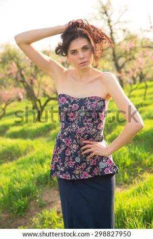 Fashion model in nature. Portrait of young beautiful woman outdoor. Stylish girl at beautiful summer alley. Brunette woman on the background of blooming sunny nature park. Natural beauty. Spring day.
