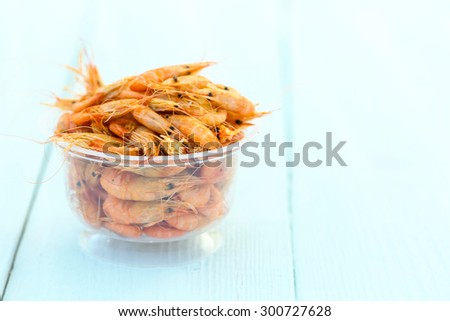 Shrimps. Sea products. One serving of cooked shrimp. Prepared shrimp on wooden blue background.