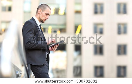 Business man using touch pad pc. Manager. Businessman working for digital tablet on the background office center building. Working out of the office. Electronic tablet. Serious man using pad computer.