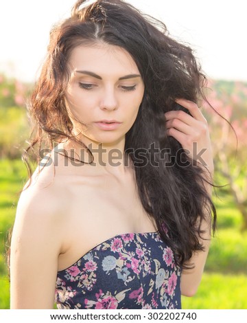 Portrait beautiful woman on the background of spring pink flowering trees. Brunette woman on a background blossoming spring garden. Space for text. Woman nature concept. Brunette woman. Spring garden.