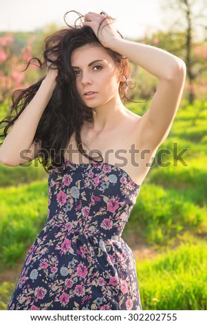 Portrait beautiful woman on the background of spring pink flowering trees. Brunette woman on a background blossoming spring garden. Space for text. Woman nature concept. Brunette woman. Spring garden.