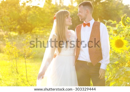 Wedding. Bride and groom. Newlyweds. Love. Photo in a yellow shade. Young couple in the glow of sunset. Happy newlyweds on the background of nature and flowers sunflower.  Young family. Happy couple.