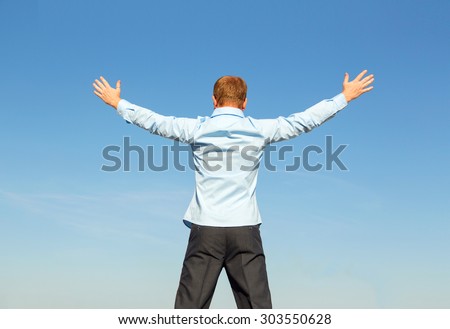 Man standing and looking the skyline. Cheering man open arms at blue sky. Businessman relaxing. happy young man standing with open arms. People outdoors.