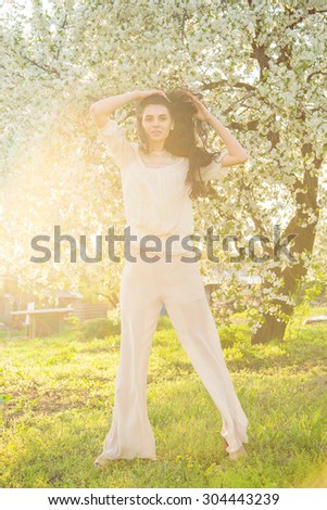 Portrait beautiful brunette woman in sunset light. Woman on nature background summer / spring. Enjoying the nature. Young woman arms raised enjoying the fresh air. Fashion woman model.
