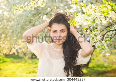Portrait beautiful brunette woman in sunset light. Woman on nature background summer / spring. Enjoying the nature. Young woman arms raised enjoying the fresh air. Fashion woman model.