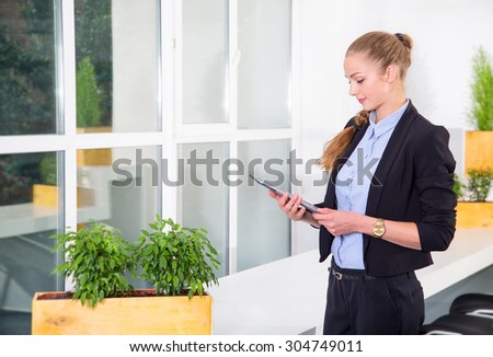 Portrait beautiful woman on the background of modern business office. Modern businesswoman holding tablet computer on background office space.