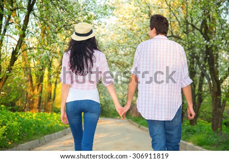 Love story. Man and woman turn back and go on the road in the distance. Happy couple holding hands looking in the sunset. Love couple in love romantic road summer field happy. Travel, tourism, stroll.