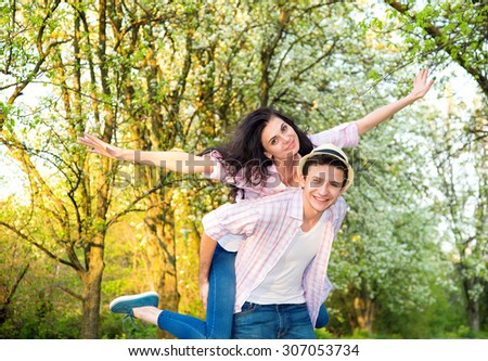 Happy loving couple arms outstretched on the summer park background. Happy people. Young couple in the countryside. Smiling couple having fun in park.