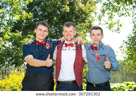 Happy groom and his friends. Group of young men in red bow tie. Cheerful friends. Three friends outdoors. Wedding day. Three young friends happy. Thumbs up friends men.
