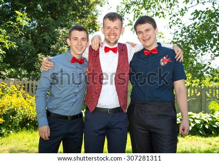 Happy groom and his friends. Group of young men in red bow tie. Cheerful friends. Three friends outdoors. Wedding day. Three young friends happy.