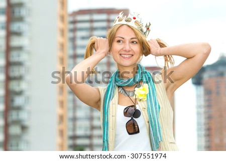I am a woman! I am the queen! Happy emotional woman with a crown on his head against the background of the city. Woman modern queen. Beautiful young blonde woman points to her crown on her head.