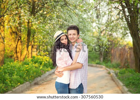 Couple hugging each other on the background of the spring park. Man and woman in love with each other. Man and woman together - love story. Spring, summer, autumn seasons for amorous adventures.