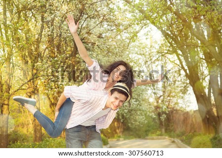Happy loving couple arms outstretched on the summer park background. Happy people. Young couple in the countryside. Smiling couple having fun in park.