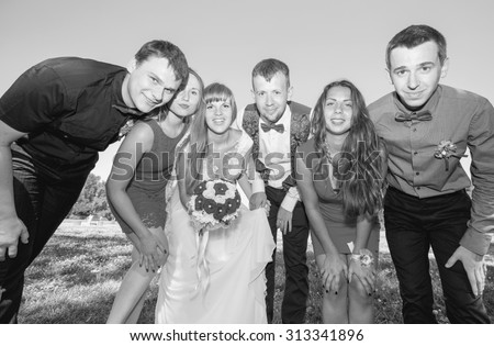 Wedding group of friends. Bride and groom with friends. Black and white image. Just married. Group of young friends make selfie photo with smart phone camera in wedding day. Funny people on the park.