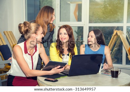 Working days in the women\'s team. Four young women - office staff. Discussion of joint work on the project. Female business. Women working in the office at the computer. Group of women. Toned image.