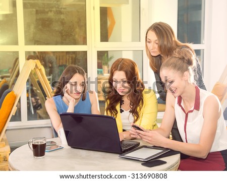 Working day. Office life. Work in the women\'s team. Four young women - office staff. Meeting. Discussion of the project. Women\'s business. Women working in the office at the computer. Tinted image.