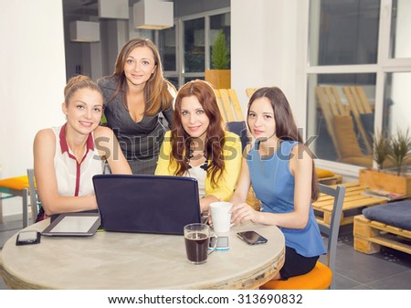 Working day. Office life. Work in the women\'s team. Four young women - office staff. Meeting. Discussion of the project. Women\'s business. Women working in the office at the computer. Tinted image.