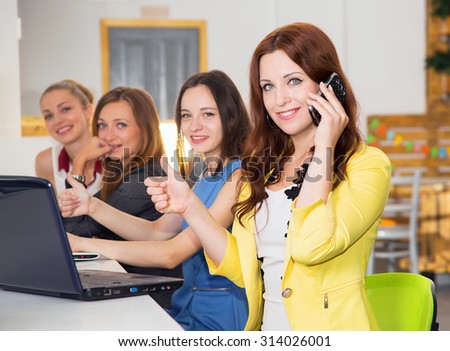 Business woman raised her thumb up. She\'s talking on the phone. Successful telephone conversation with the customer. Make a bargain in the on-line store. Women working at the computer. Toned image.