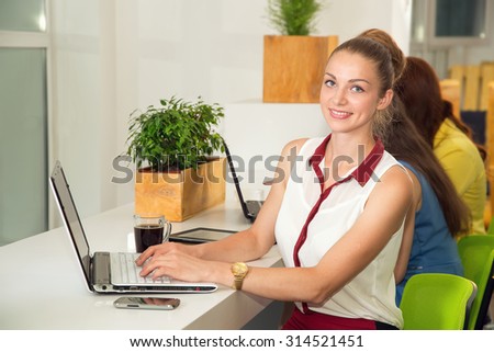 Woman at workplace. Portrait beautiful woman on the background of modern business office. Young business woman working in office. Woman student look at the computer. Green office. Life style.