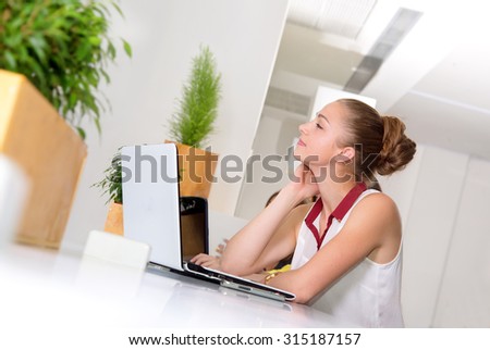 Woman dreaming about vacation or about new purchases. Woman dreams. Woman with laptop. Young woman working at a laptop in the office. Business woman, office worker. Girl student to work at a computer.