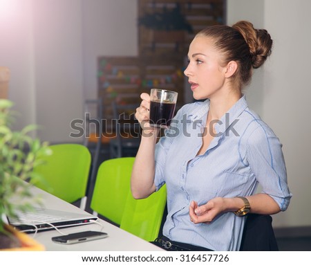 Woman with laptop. Young woman drinking morning coffee and works at a laptop in the office. Business woman - office worker. Girl student to work at a computer and drinking coffee. Evening coffee break