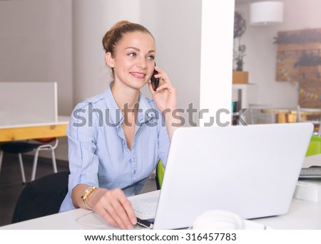 Woman working at a laptop. Business woman sales manager talking on the mobile phone with a client. Working in the office. Service support, customer service. Female sales manager or insurance agent.