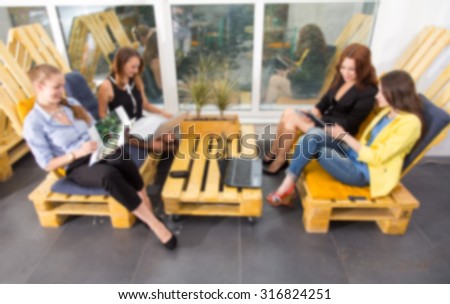 Blurred image. Blurred people. Working day. Office life. Meeting. Work in the women\'s team. Group business women - office staff. Discussion of the project. Women students. Blurred background image.
