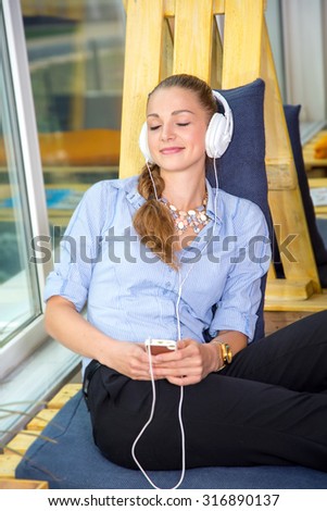 Woman wearing headphones listening to music on your phone. Feel relaxed with the help of music. Young beautiful girl listening to music on headphones during a work break. Woman student. Life style.