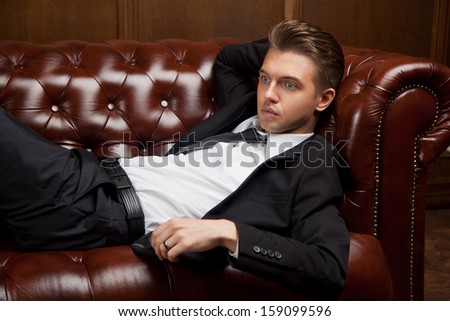 stylish young man in a suit lying on the couch
