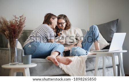 Beautiful lesbian family with dog talking and spending time together at home on sofa