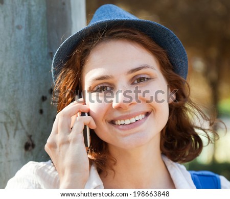 Beautiful girl speaks on mobile phone in park, in soft focus